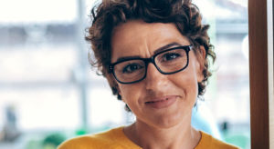 Woman wearing glasses, smiling.